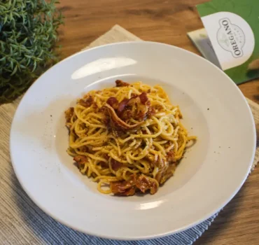 Na zdjęciu widoczne jest danie z makaronu spaghetti z dodatkiem suszonego mięsa, przypraw, podane na białym talerzu.