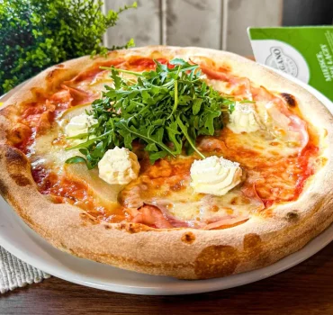 Pizza z szynką, serkiem ricotta, gruszką i rukolą na chrupiącym cieście.